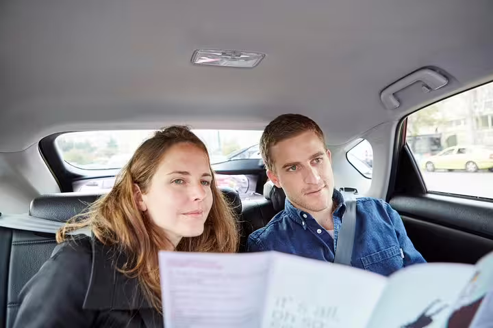 Couple riding in private car with guide notes for Athens half-day sightseeing ride and city highlights