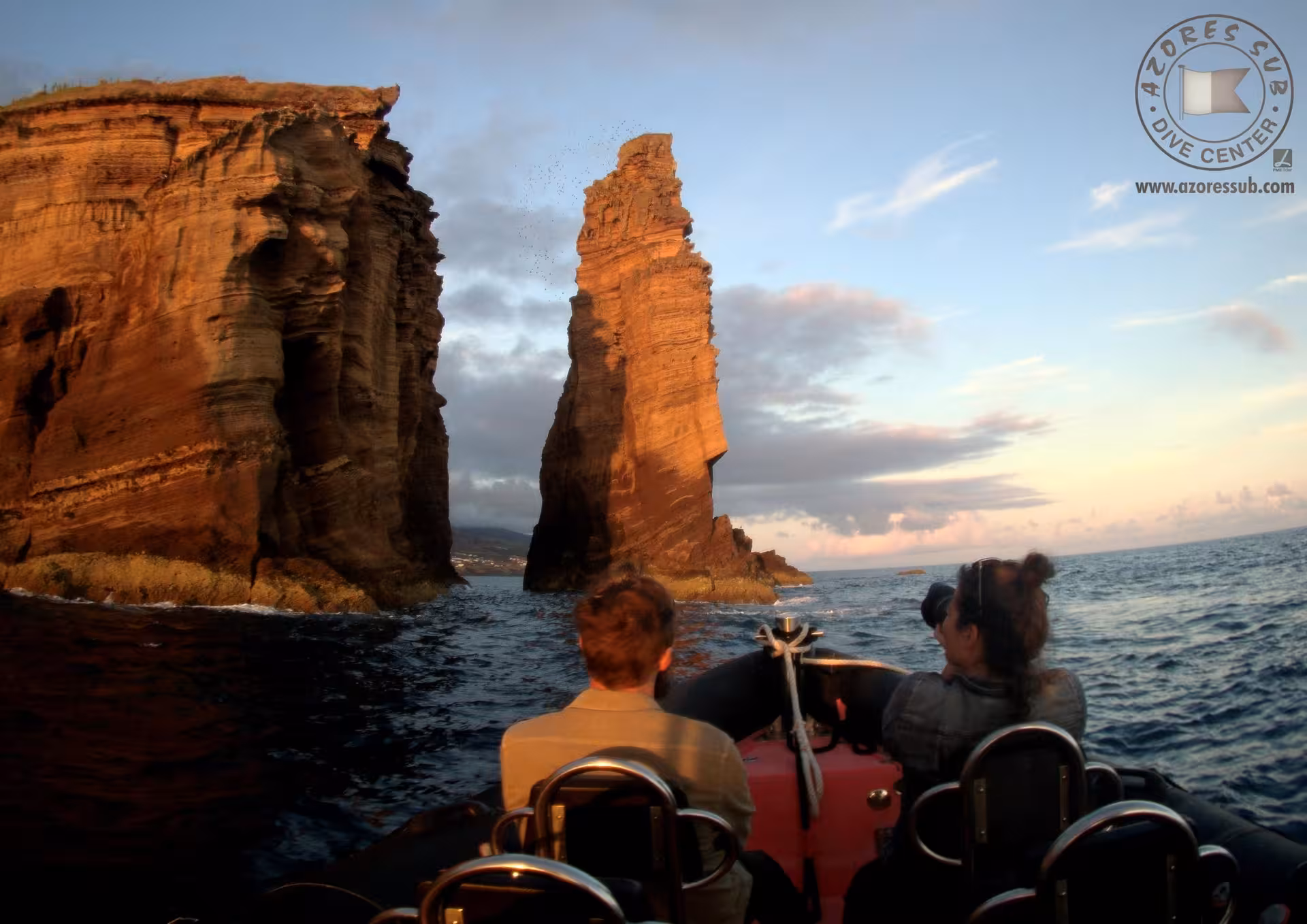 Private Azores boat tour approaching towering volcanic sea stacks at golden hour, ocean wildlife watching