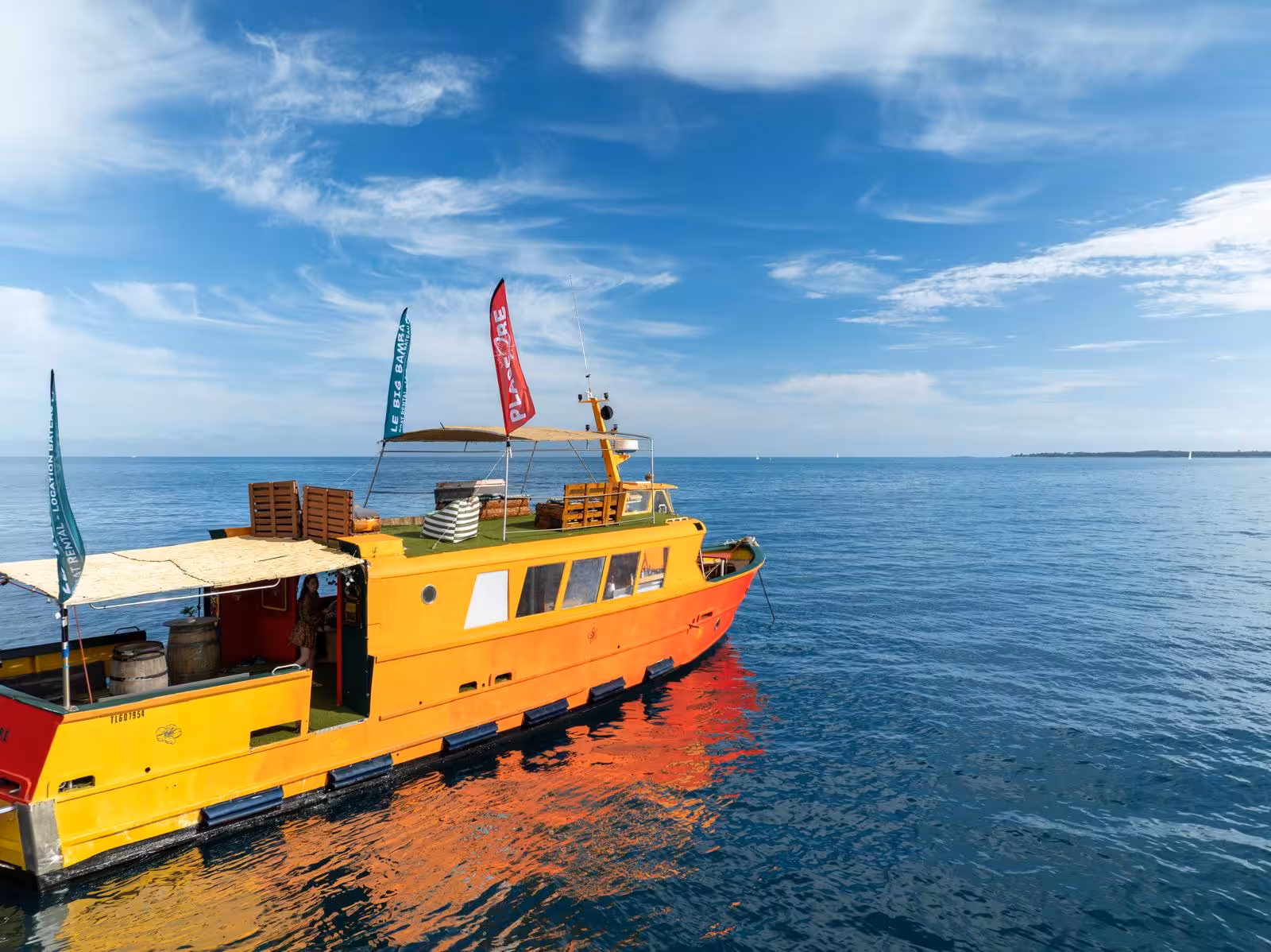 Colorful yellow and orange private party boat on calm blue waters of the French Riviera near Cannes