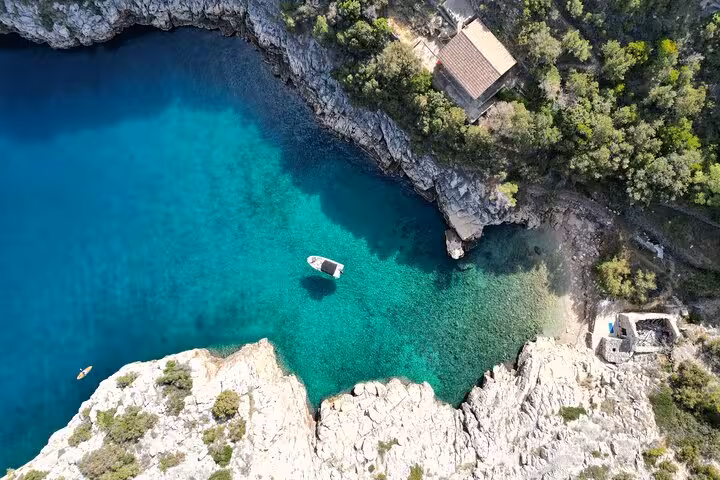 Aerial view of private boat in turquoise Adriatic cove, Croatia island tour with hidden bay and cliffs