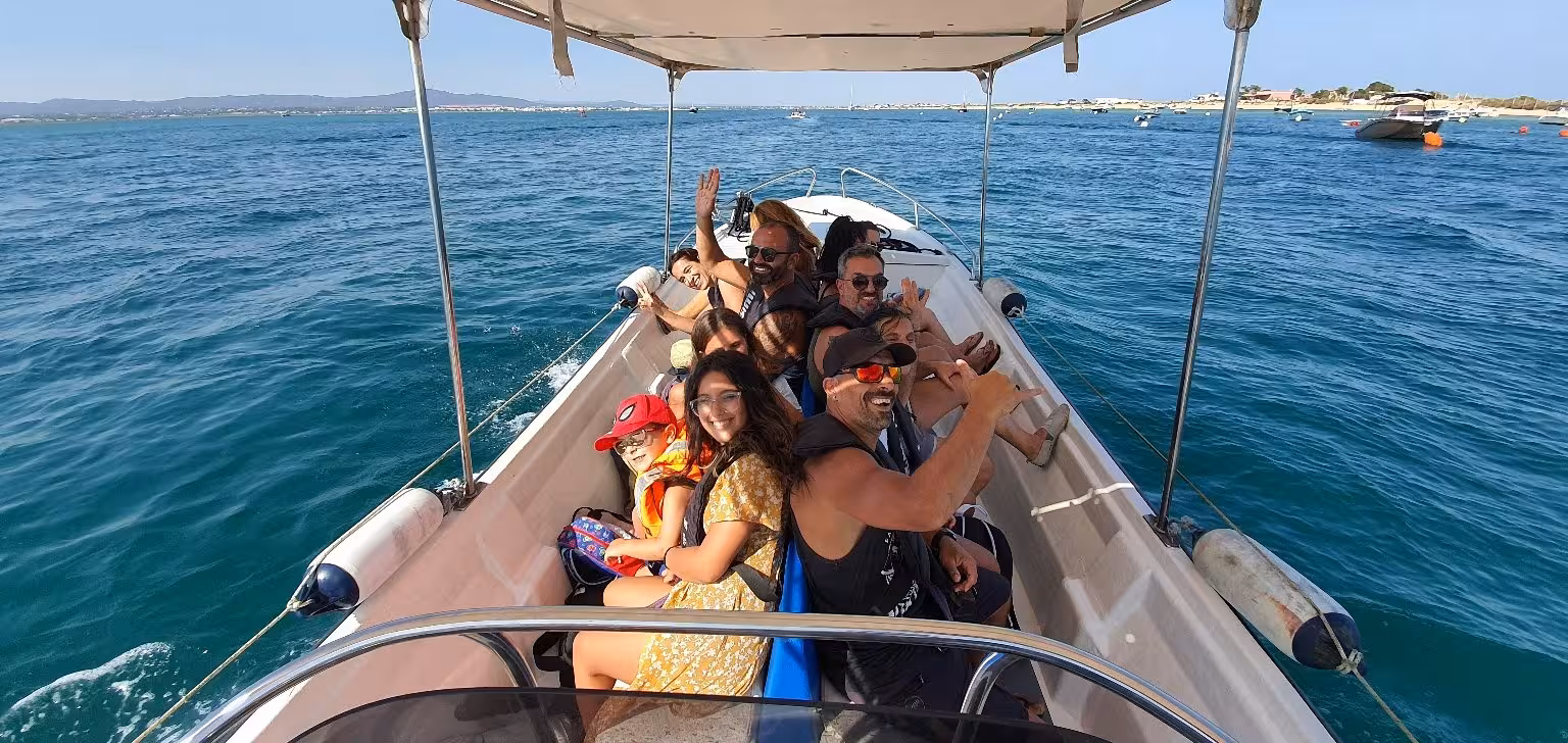 Group enjoying a lively boat tour in Ria Formosa, exploring stunning coastal views on a sunny day.