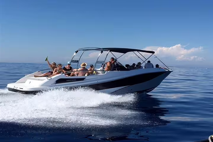 Sleek private boat gliding through clear blue waters on a sunny day during a Rio tour with barbecue and drinks.