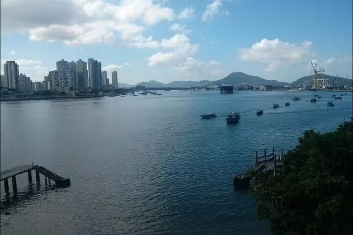 Scenic view of Santos harbor with boats and city skyline perfect for a private full-day boat tour with barbecue.