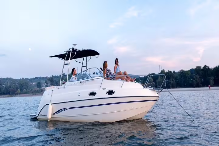 Group of friends relax on a private boat at sunset, enjoying a full-day tour in Santos with included barbecue and drinks.
