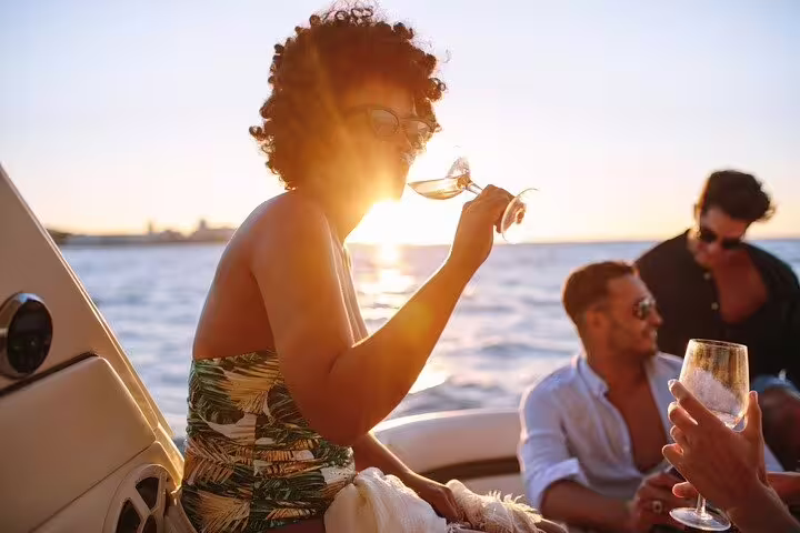 Group enjoying wine and sunset on a private boat tour in Santos, highlighting luxury and relaxation with barbecue and drinks.