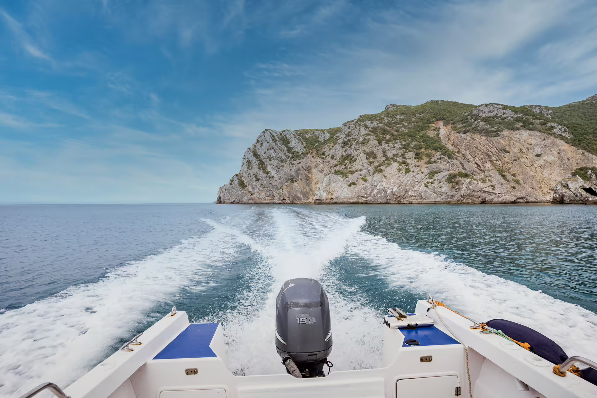 Private boat tour in Sesimbra's Arrábida Park, showcasing stunning cliffs and serene blue waters under a clear sky.