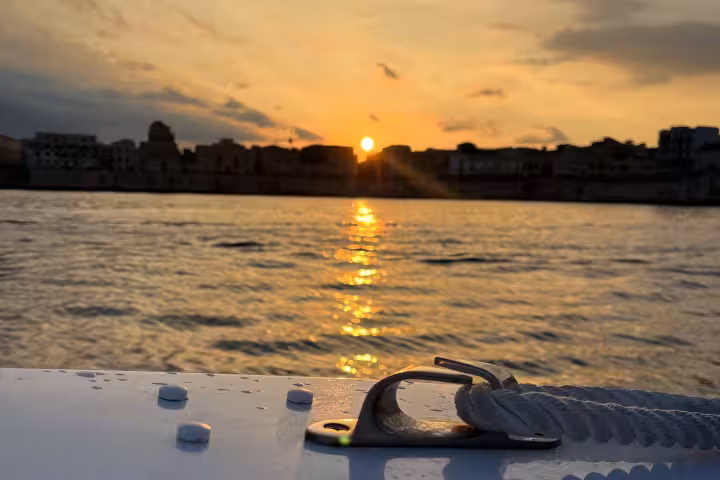 Serene sunset view from a private boat tour showcasing a stunning cityscape silhouette and golden reflections on the water.