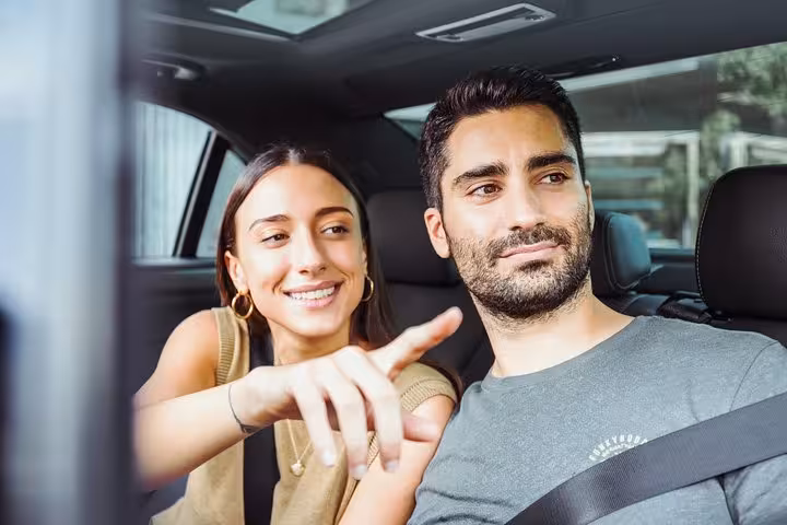 Couple in private car with driver pointing out sights during a half-day Brussels city sightseeing tour