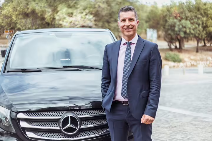 Professional private driver beside luxury Mercedes for a 2-hour Brussels sightseeing tour with hotel pickup
