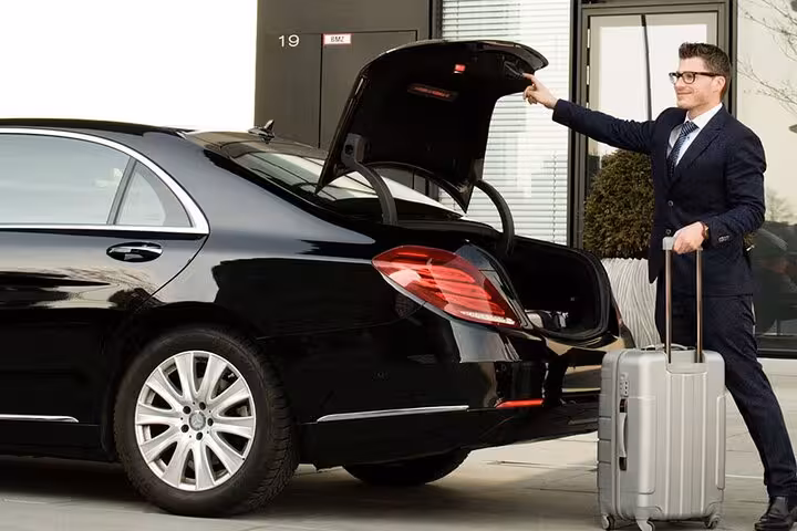 Driver loading luggage into sedan for private Cairo hotel to airport transfer, meet-and-greet with suitcase