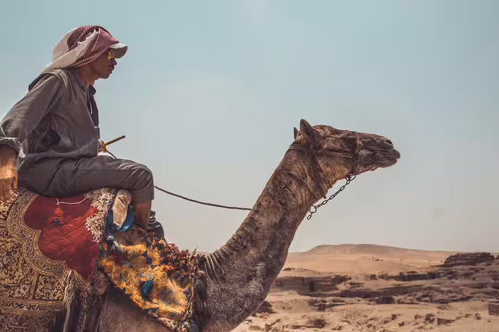 Local guide riding a camel across the Giza desert near Cairo, part of a private 2-hour camel ride around pyramids