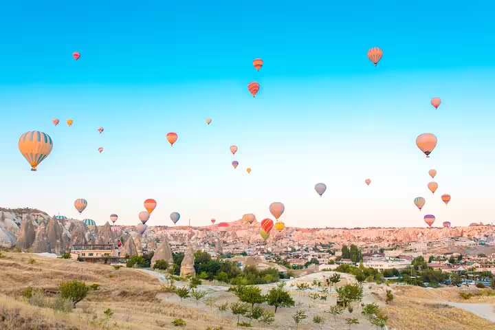 Vibrant hot air balloons soaring over Cappadocia's unique landscape, perfect for a private tour from HOTEL & ASR-NAV airport.