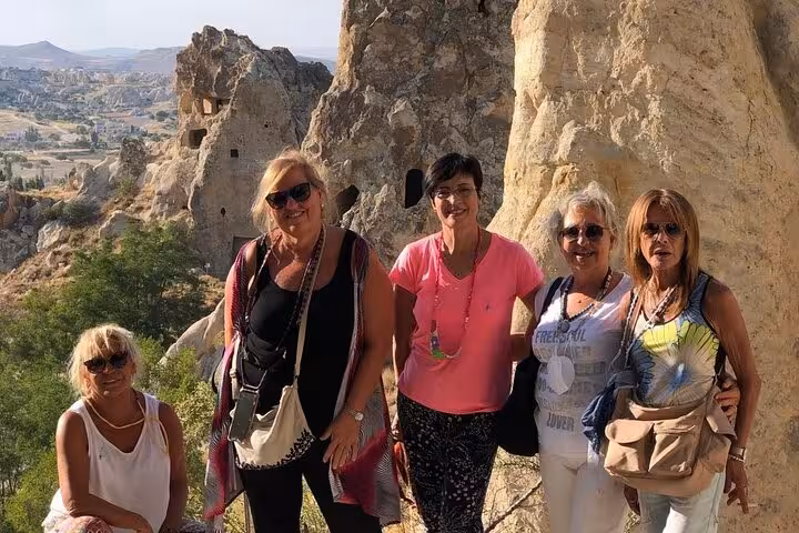 Visitors pose near Cappadocia rock-cut caves and valley views on a private tour with luxury vehicle