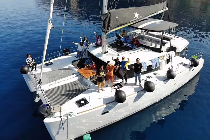 Group enjoying a tailor-made private catamaran cruise in Santorini under sunny skies on a luxurious vessel.