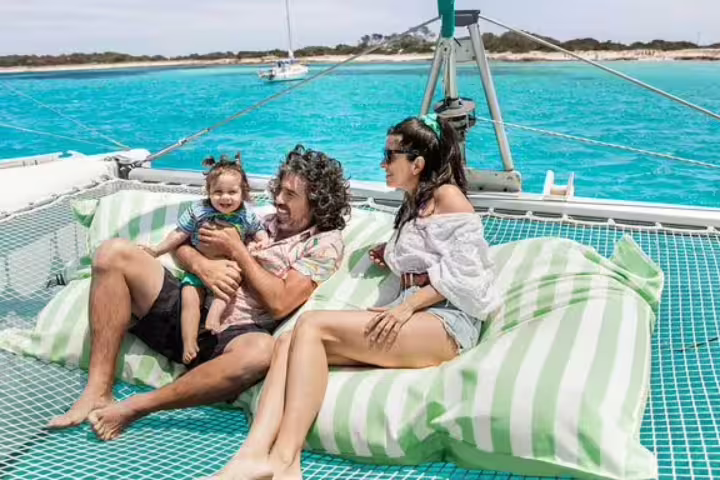 Family relaxing on a private catamaran with turquoise waters in Ibiza and Formentera, enjoying a full-day sailing trip.