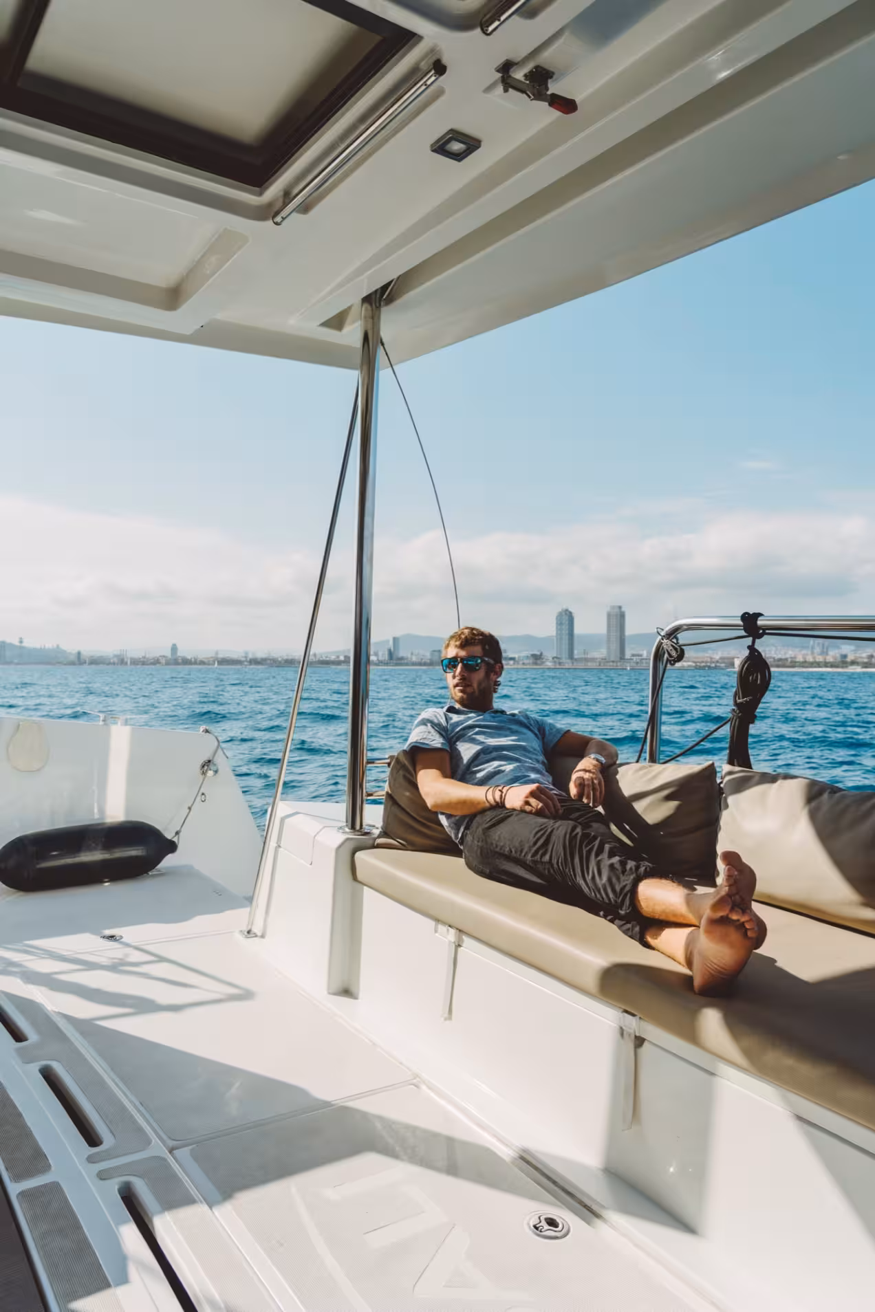 Guest relaxing on deck during a private catamaran rental, enjoying sunny Mediterranean sea views