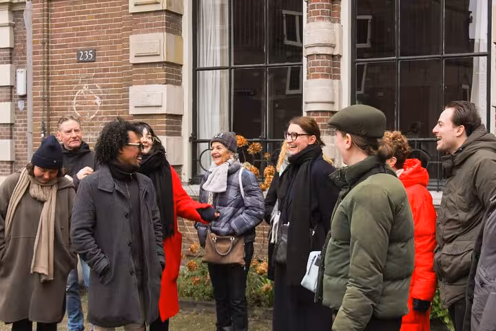 Small group meeting a local guide outside a historic Amsterdam building, private city walking experience