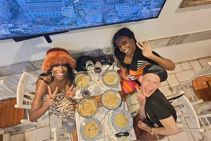Three friends enjoying pasta and wine at a private cooking class in Rome, highlighting a delightful Italian dining experience.
