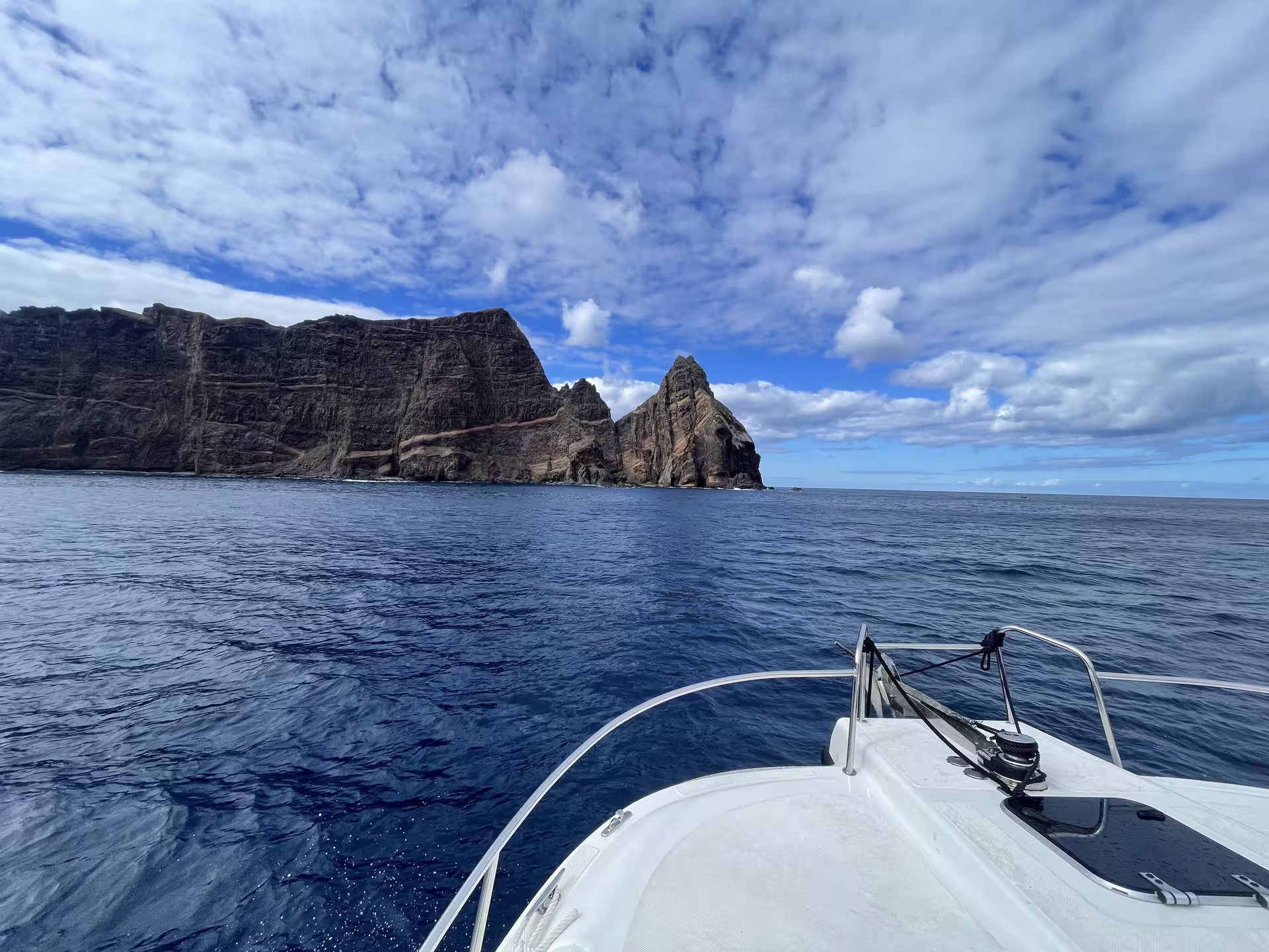 Boat approaches stunning coastal cliffs under a vibrant sky on private cruise tour.