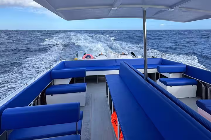 Spacious deck with blue seating on a private cruise, sailing through open sea on an adventure escape.