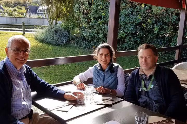 Three tourists dining outdoors at a restaurant near D-Day Beaches on a guided tour from Rouen