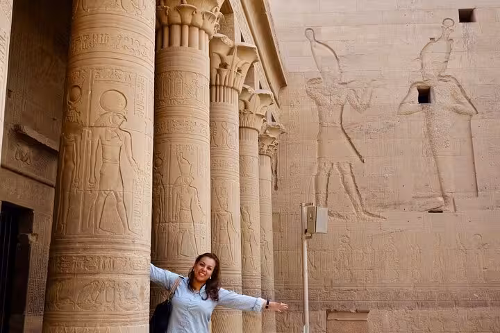Traveler at Philae Temple columns in Aswan, highlight of a private day tour from Luxor with guide