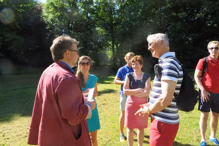 Group of tourists enjoying a guided outdoor tour discussion in a sunny park in Normandy