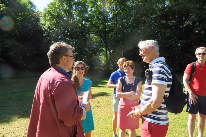 Tour guide speaking with a group of tourists in a sunny park during a private day trip in Normandy