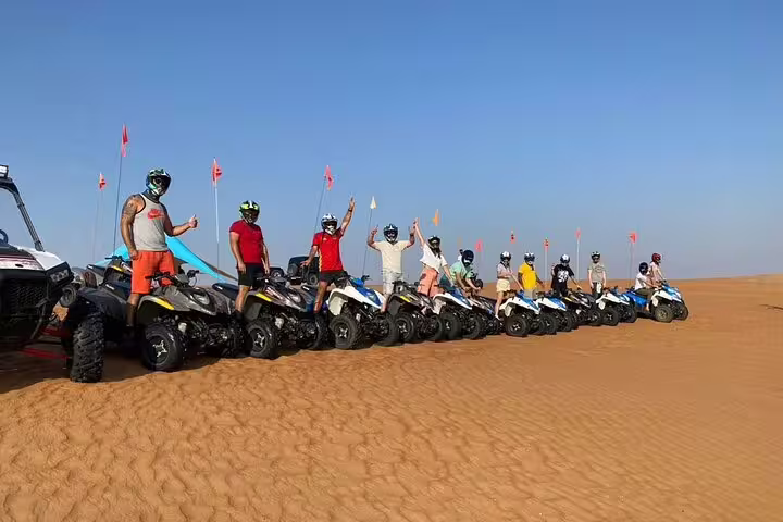 Group of adventurers on quad bikes ready for a thrilling private desert adventure, showcasing the vast sandy landscape.