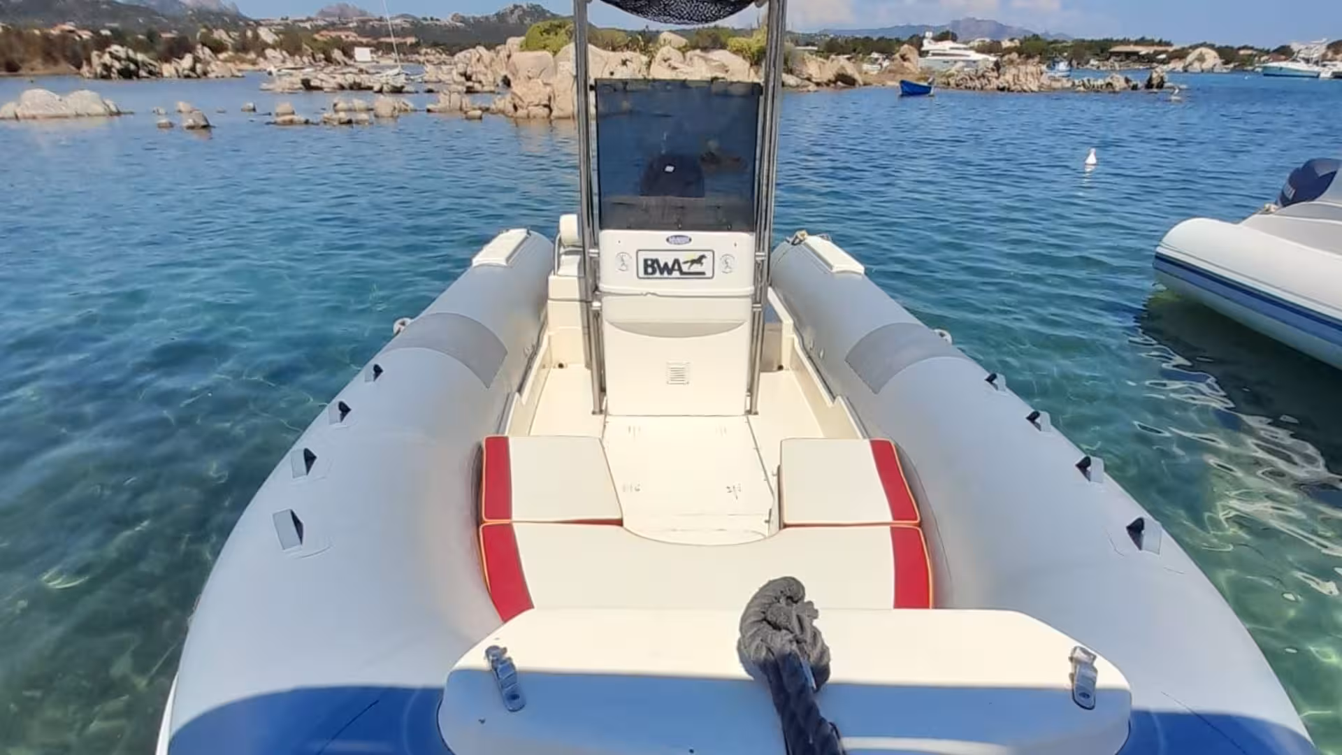Front view of a private dinghy ready for a tour between Tavolara and La Maddalena, showcasing pristine turquoise waters.