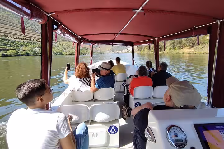 Guests relax on a private Douro River boat cruise with guide, enjoying scenic vineyards and Port wine