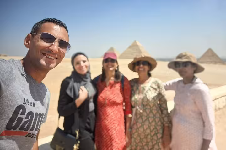 Smiling group takes a selfie with the majestic Pyramids of Giza in the background during a private Egypt tour.