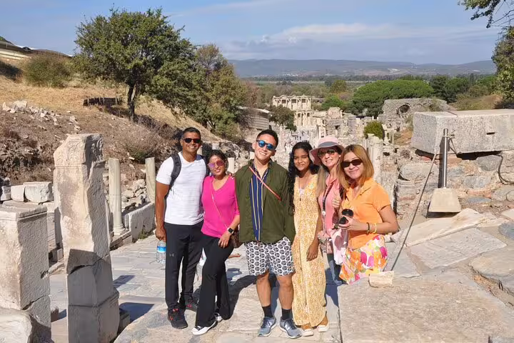 Happy visitors explore ancient ruins on a private Ephesus tour, featuring Celsus Library with included entry fees and lunch.