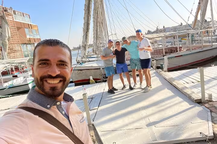 Travelers posing at the Nile dock beside a traditional felucca, ready for a private Cairo felucca boat ride