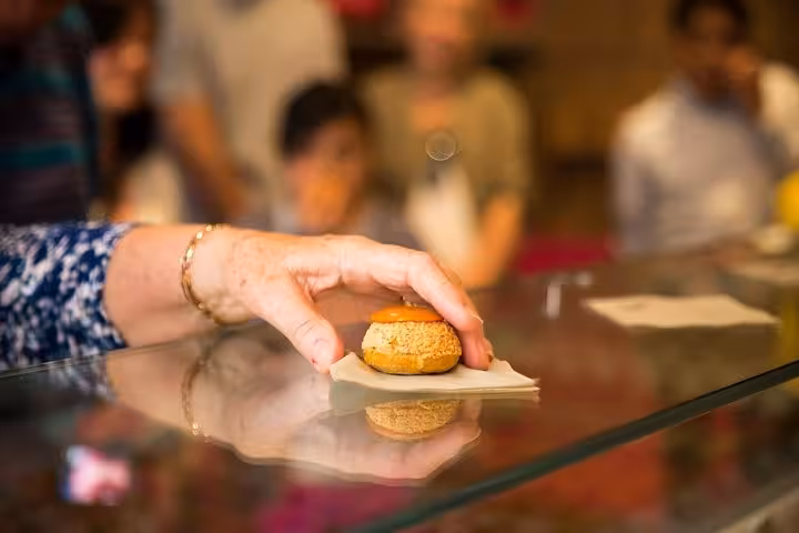 A hand picking up a delicate pastry during a private food tour in Paris, highlighting French culinary delights.