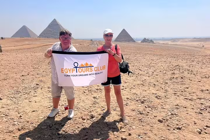 Couple holding tour banner on private Giza Pyramids day trip, Cairo with Grand Egyptian Museum visit included