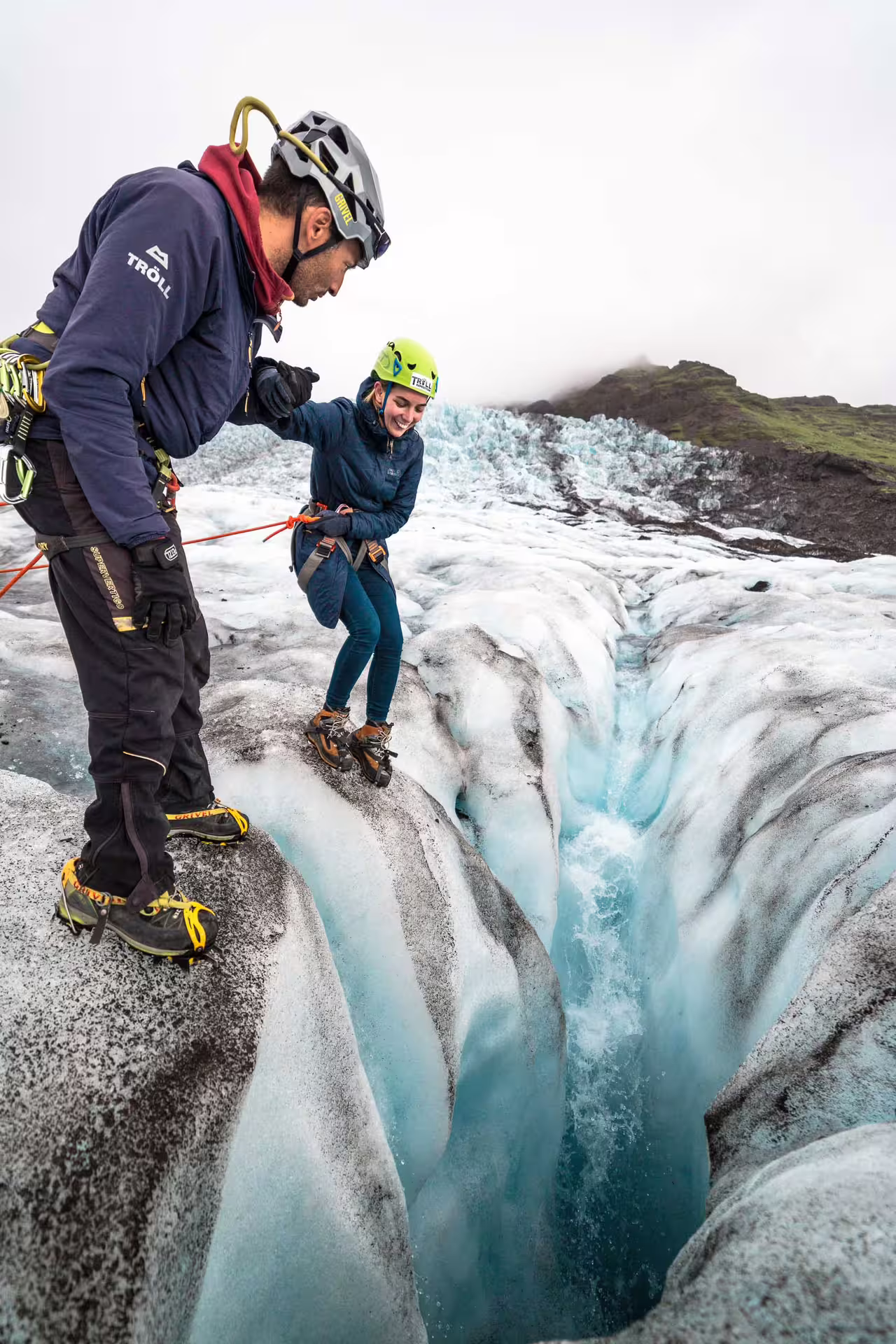 Two hikers with helmets and crampons exploring a glacial crevasse on Vatnajokull glacier in Skaftafell