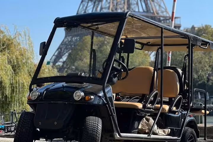 Black golf cart parked near the Eiffel Tower in Paris on a sunny day