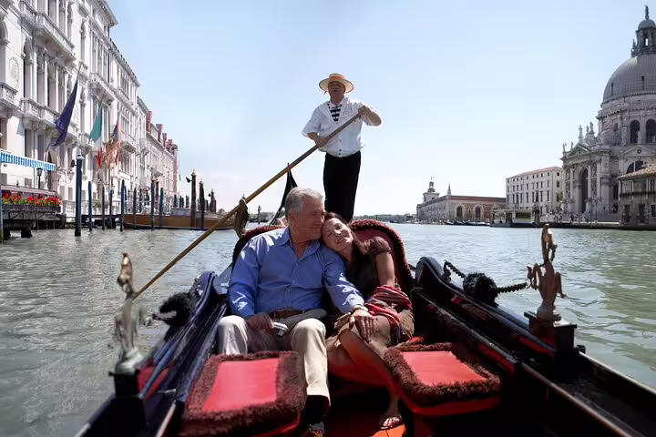 Romantic couple relaxing on a private gondola ride along Venice’s Grand Canal with historic palaces and basilica views