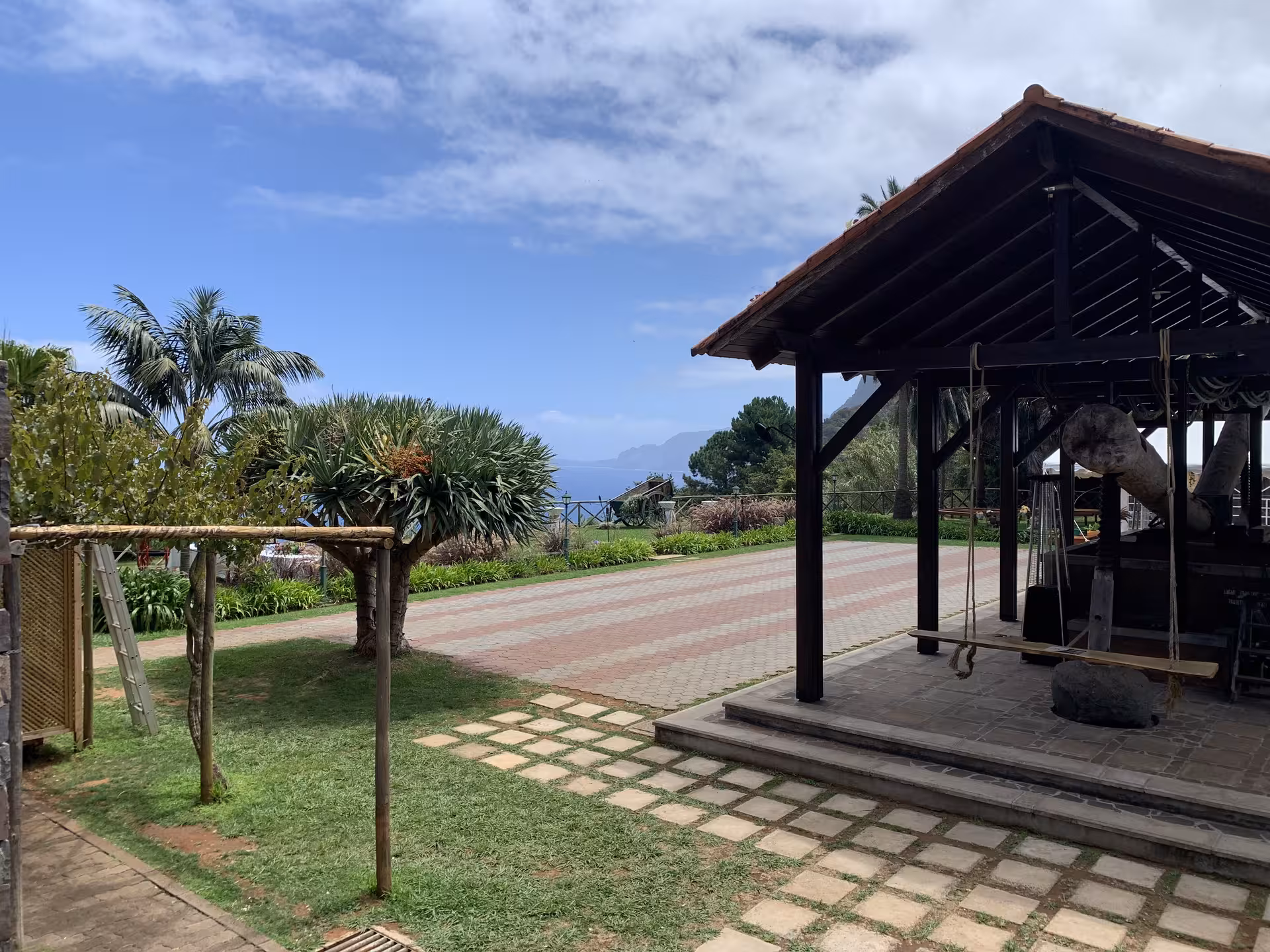Charming garden view with palm trees and rustic wooden shelter under a bright blue sky, perfect for private excursions.