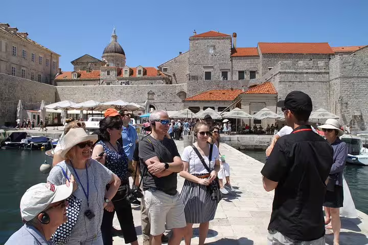 Private guide briefing guests at Dubrovnik Old Town harbor with medieval city walls on the combo tour
