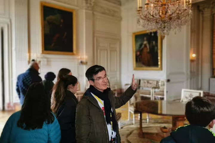 Private guide leading visitors through Versailles Palace salon, chandeliers and paintings on day tour from Paris