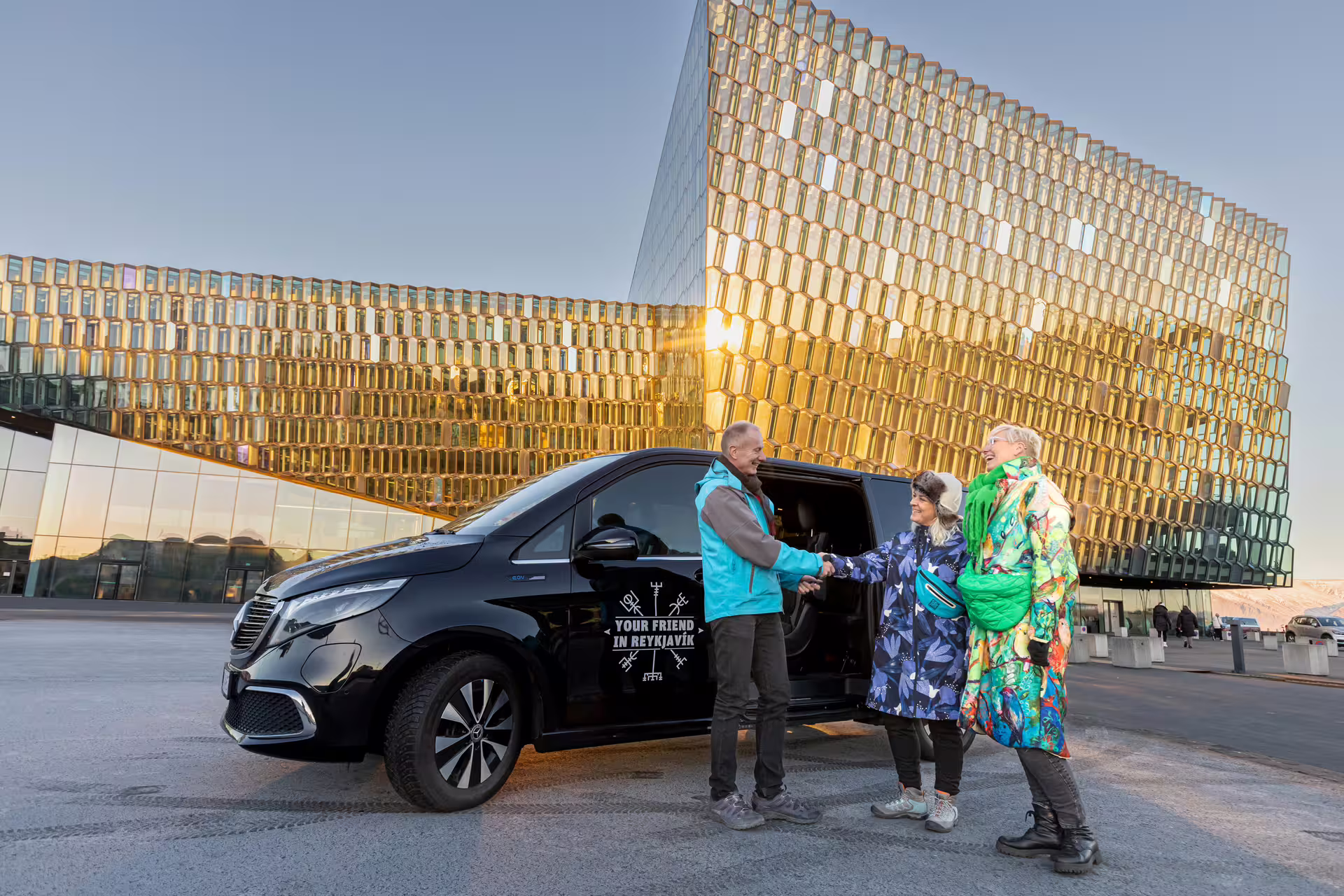 Expert driver guide from Your Friend In Reykjavik greeting travelers outside Harpa concert hall for private 3 hour Reykjavik Driving Tour
