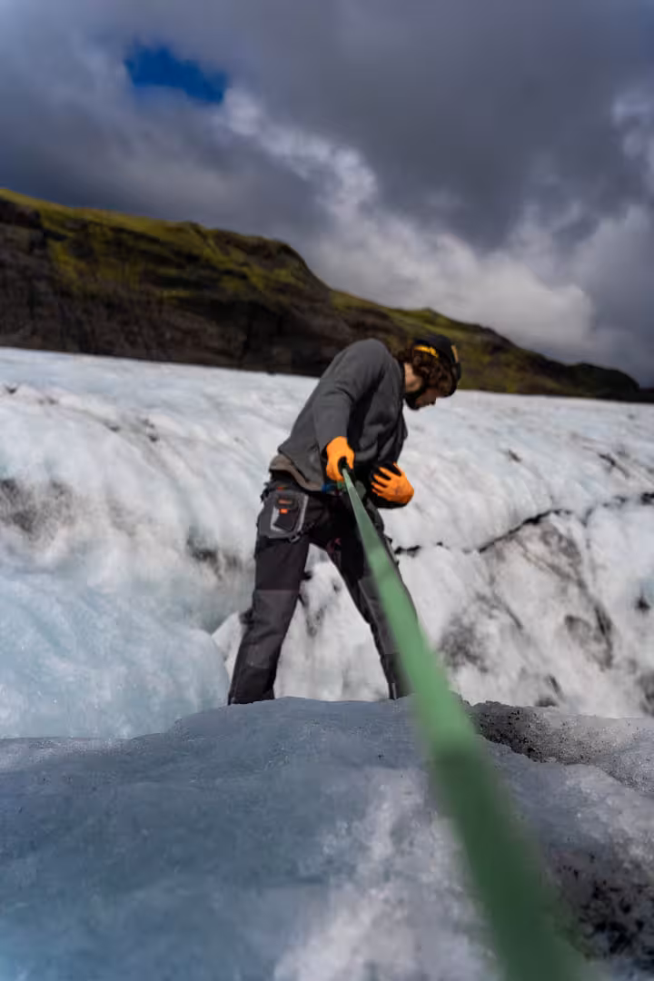 Guide holding green rope on Solheimajokull glacier ice surface during private glacier hike Iceland