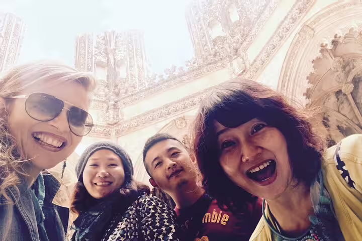 Happy tourists enjoying a guided private day tour at the stunning architecture of Batalha Monastery in Portugal.