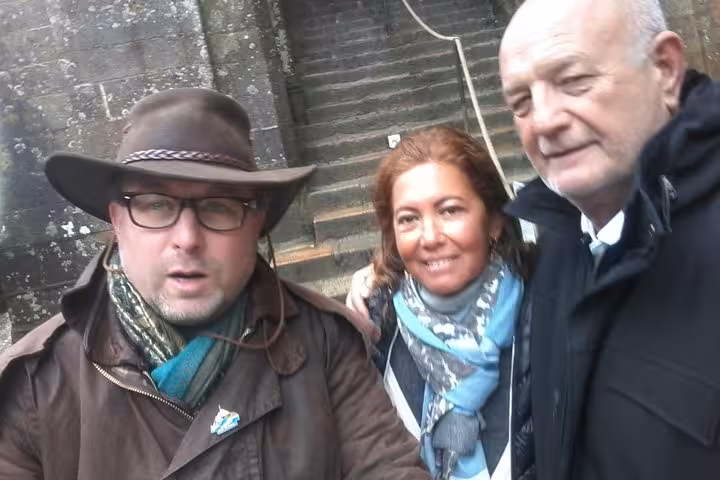 Three smiling tourists posing together during a guided tour at Mont Saint-Michel