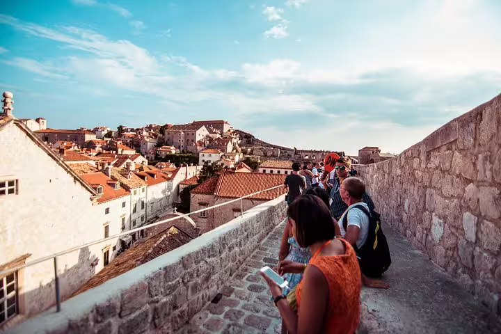 Guided private walk on the Ancient City Walls with Old Town views and terracotta rooftops at sunset
