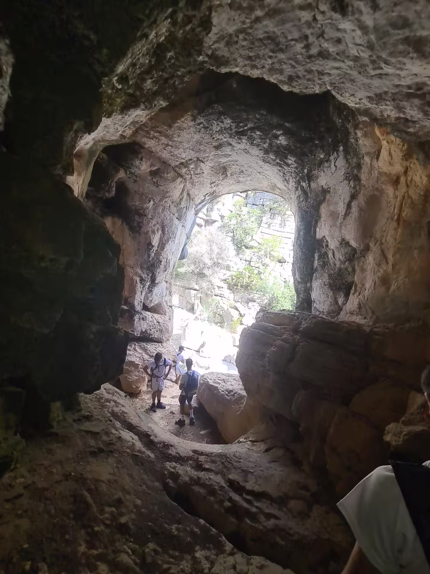 Hikers exploring a rocky cave entrance at Canuto de la Utrera, highlighting the adventure of private hiking tours.