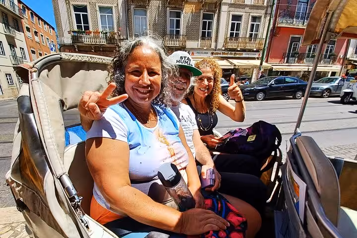Friends smiling in a tuk tuk during a 2-hour private historic Lisbon tour past colorful city buildings