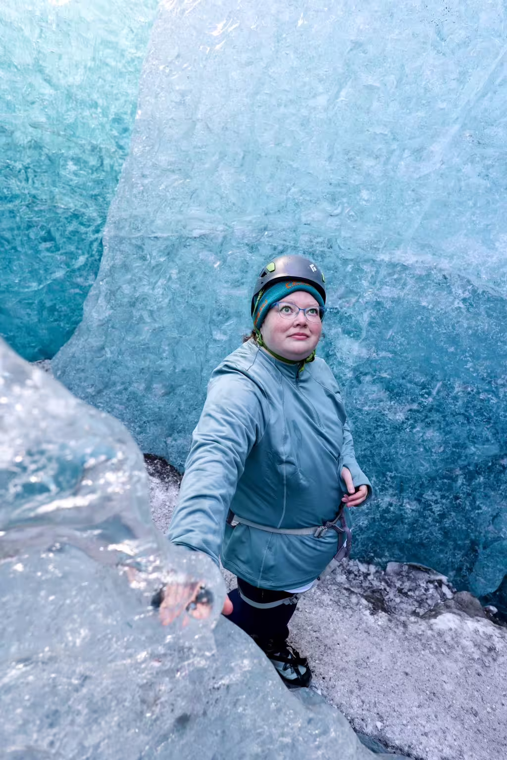 A helmeted woman navigates glowing blue glacier walls during an exclusive private ice cave adventure tour in Iceland.